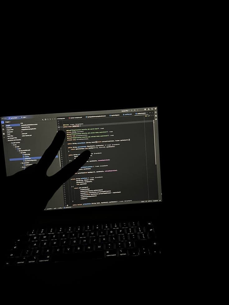 Silueta de mano haciendo signo de paz frente a pantalla con código de programación.
